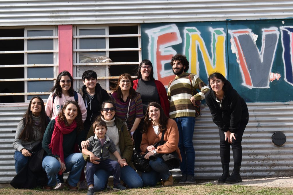 Once personas posan para la foto. Detras hay una estructura con grafitis
